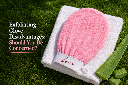 A Zomno™ exfoliating glove resting on a clean folded towel with a small aloe leaf beside it